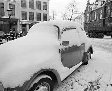 880248 Afbeelding van een besneeuwde Volkswagen Kever, geparkeerd bij de Pausdam te Utrecht, met op de achtergrond de ...